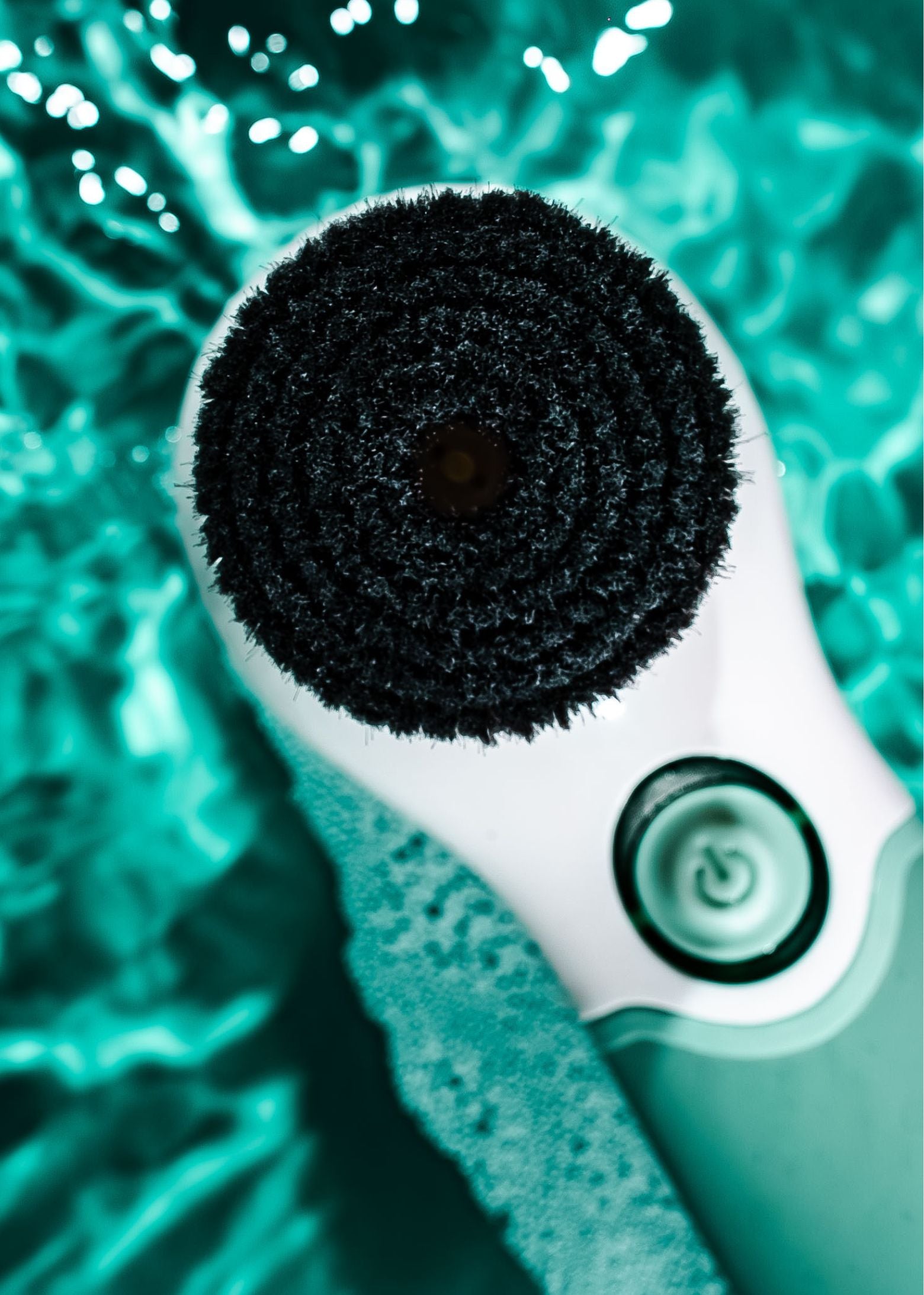 Cleaning brush with black bristle head on a teal background
